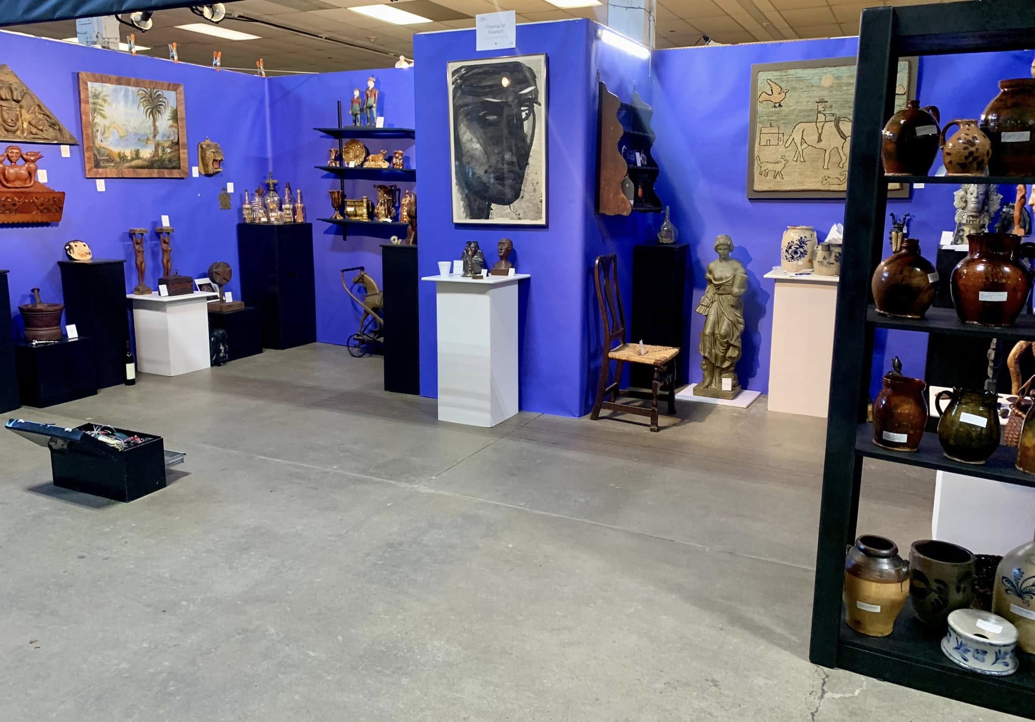 Art gallery space with blue walls displaying sculptures and artifacts